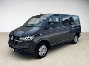 Grauer Volkswagen Transporter T6, seitliche Ansicht, auf hellem Boden in einem leeren Raum.