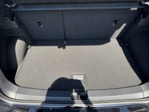 Offener Kofferraum eines Autos, grauer Teppichboden, Schatten einer Person sichtbar.
