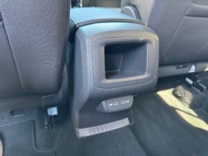 Leerer schwarzer Konsoleneinsatz im Auto mit strukturiertem Kunststoff und dunklem Teppichboden.