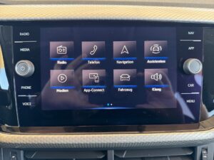 Ein Autoinformationsdisplay zeigt Symbole für Radio, Telefon, Navigation und mehr auf schwarzem Hintergrund.