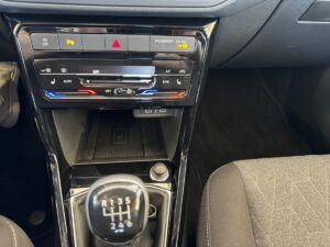 Innenraum eines Autos mit manuellem Schaltknüppel, Klimaanlagensteuerung, schwarzer Kunststoffverkleidung.