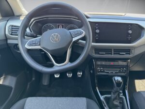 Lenkrad und Armaturenbrett eines modernen Autos mit digitalen Anzeigen, in Schwarz und Grau.