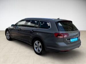 Grauer Volkswagen-Kombi in hellem Raum, seitliche Rückansicht.
