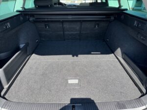 Leerer Kofferraum eines Autos mit grauem Teppich und schwarzen Seitenteilen.