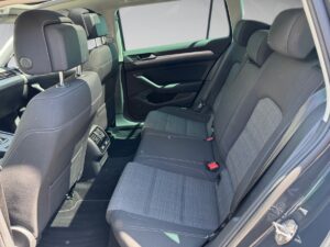 Rückseite eines Autos mit grauen Stoffpolstern, Sonnenlicht betont die geräumigen Sitze.