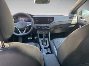 Innenansicht eines Autos mit schwarzem Armaturenbrett, Lenkrad mit VW-Logo.