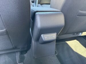 Rücksitz eines Autos mit einer schwarzen Armlehne und eingebauter Steuerungspanel.
