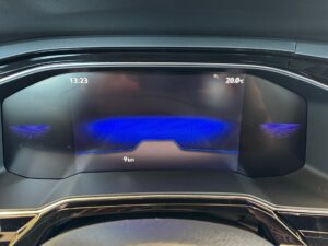 Digitales Auto-Display mit blauer Grafik, zeigt Uhrzeit, Temperatur und Kilometerstand an.