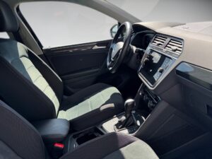 Innenraum eines modernen Autos, schwarze Sitze, großes Display, Lenkrad links, Tageslicht.