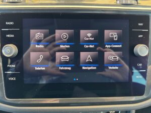 Auto-Infotainment-Bildschirm mit Symbolen für Radio, Medien, Navigation und mehr in dunklen Farben.