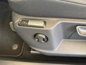 Nahaufnahme eines ergonomischen Sitz-Schalters in einem Auto, graue Töne, modern gestaltet.