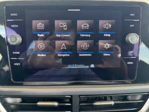 Auto-Infotainmentbildschirm mit Menü, dunkles Design, Reflexion der Kamera.