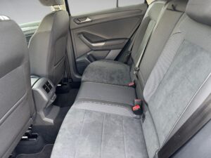 Rückbank eines Autos, graue Sitze, moderne Innenausstattung, rote Sicherheitsgurtschlösser.