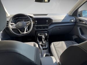 Innenraum eines VW-Autos in Schwarz mit Sitzplätzen, lenkrad, und Infotainmentsystem.