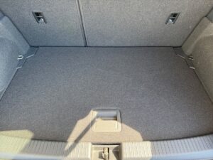 Kofferraum eines Autos mit grauem Teppichboden und zwei Befestigungspunkten an der Rückwand.