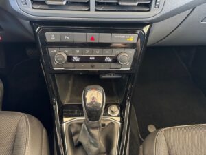 Mittelkonsole eines Autos mit Touchscreen und schwarzen Knöpfen, rote und gelbe Lichtanzeigen.
