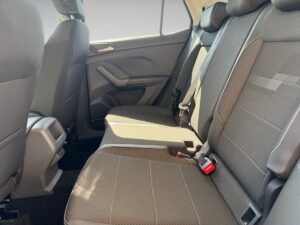 Rücksitze eines Autos mit grauen Polstern und roten Gurtschlössern in hellem Licht.