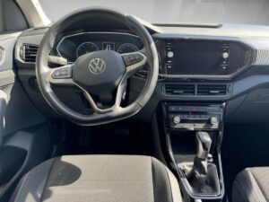 Lenkrad und Armaturenbrett eines Autos mit VW-Emblem, moderne Anzeige, schwarz-graue Farben.