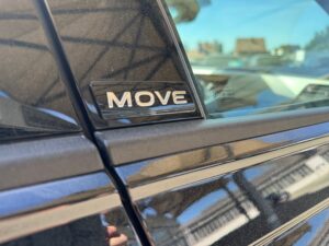 Nahaufnahme eines schwarzen Autos mit "MOVE"-Emblem an der Seite.