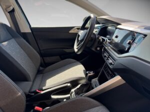 Modernes Autoinnenraum-Design mit grauen Stoffen und einem großen Display, Sonnenlicht fällt ein.