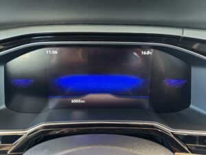 Digitales Armaturenbrett mit blauer Grafik, zeigt Uhrzeit, Temperatur und Kilometerstand an.