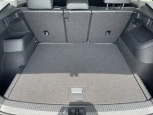 Leerer, grauer Kofferraum eines Autos, Rücksitze hochgeklappt, helle Beleuchtung.