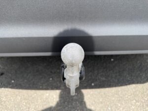 Anhänger-Kupplung eines Autos, grau, leichte Abnutzungsspuren, auf Asphaltboden.