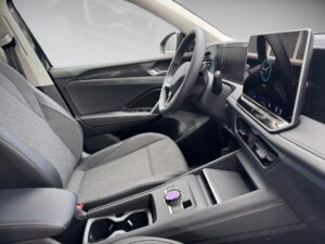 Innenraum eines Autos mit grauen Sitzen, Lenkrad und großem Touchscreen auf der Konsole.