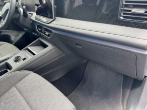 Grauer Autoinnenraum mit digitalem Display, modernem Armaturenbrett und Stoffpolstern.