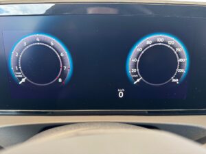 Ein digitales Armaturenbrett zeigt Drehzahlmesser und Tachometer mit blauer Beleuchtung.