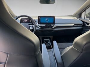 Autoinnenraum mit modernem Armaturenbrett, großem Bildschirm, grauen Ledersitzen.