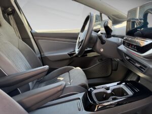 Innenraum eines modernen Autos mit grauen Sitzen, elegantem Lenkrad und digitalem Display.