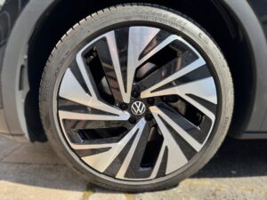 Nahaufnahme einer Pkw-Felge mit interessantem, schwarz-silbernem Design und VW-Logo in der Mitte.