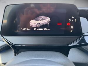 Autodisplay zeigt Ladezustand (93%) und Reichweite (356 km). Heller Hintergrund, rotes "PARK".