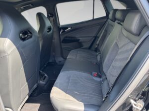 Rückbank eines Autos mit grauem Stoffbezug, schwarzer Innenraum, moderne und saubere Ausstattung.