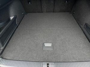 Rückansicht eines leeren Kofferraums, grauer Teppichboden, dunkle Seitenverkleidungen.