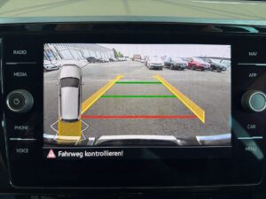 Rückfahrkamera-Ansicht eines Autos auf einem Parkplatz, mit farbigen Leitlinien.