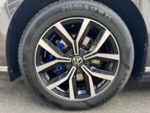 Ein VW-Rad mit schwarzem Reifen und blauer Bremse, silber-schwarze Felge.
