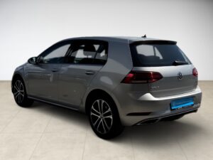 Grauer Volkswagen Golf von hinten links, auf hellem Boden stehend.