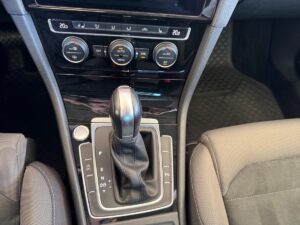 Automatikgetriebe in einem Auto, schwarze Schalthebel, mehrere Bedienelemente und Anzeigen.