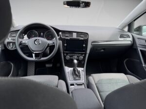 Innenraum eines Autos mit schwarzem Lenkrad und Armaturenbrett, grauer Stoffbesatz.