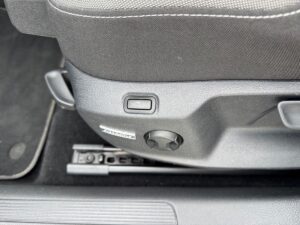 Autositzeinstellungssteuerung in einem Auto, mit schwarzer Farbe und Textur, zwei Drehknöpfe sichtbar.