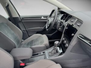 Innenraum eines modernen Autos, graue Sitze, Lenkrad links, Armaturenbrett mit Bildschirm.