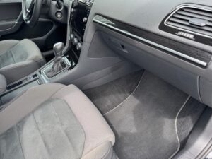 Innenraum eines Autos, sichtbar sind Schalthebel, Sitze und graue Polsterung.