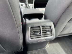 Rückansicht eines Autositzes mit schwarzer Stoffpolsterung und Lüftungsgitter in der Mittelkonsole.