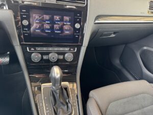 Auto-Innenraum: Mittelkonsole mit Touchscreen-Display, Gangschaltung und Bedienelementen in Schwarz.