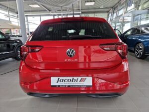 Roter VW Polo von hinten in einem Autohaus, glänzende Oberfläche, moderne Architektur.