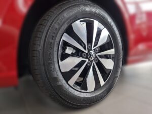 Ein Autoreifen eines roten Fahrzeugs mit stilvollem, schwarz-silbernem Radkappen-Design.