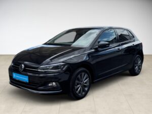 Ein schwarzer VW Polo mit glänzendem Lack und auffälligen Felgen in einem hellen Raum.