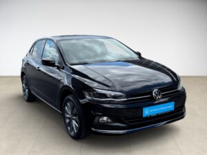 Schwarzer VW Polo, glänzend, in einem Showroom, zeigt eine dynamische Frontansicht.
